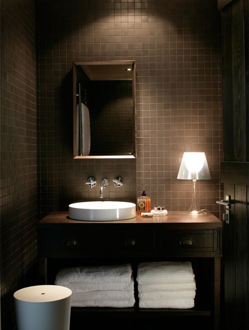hình ảnh phòng tắm màu nâu chủ đạo vói gạch ốp lát màu nâu, bồn rửa mặt màu trắng, bên cạnh là đèn bàn sang trọng