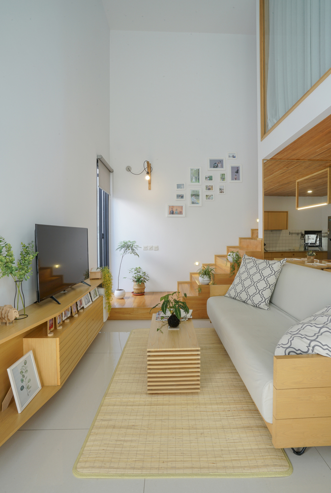 hình ảnh phòng khách với sofa ghi trắng, chiếu trải, tủ kệ tivi bằng gỗ màu sáng