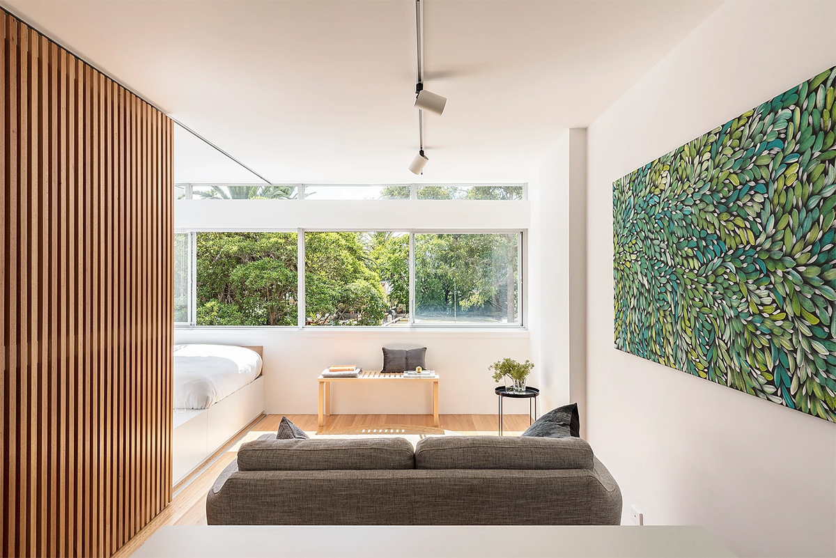 góc phòng khách trong căn hộ nhỏ 24m2 với ghế sofa màu xám, tranh tường lớn màu xanh lá