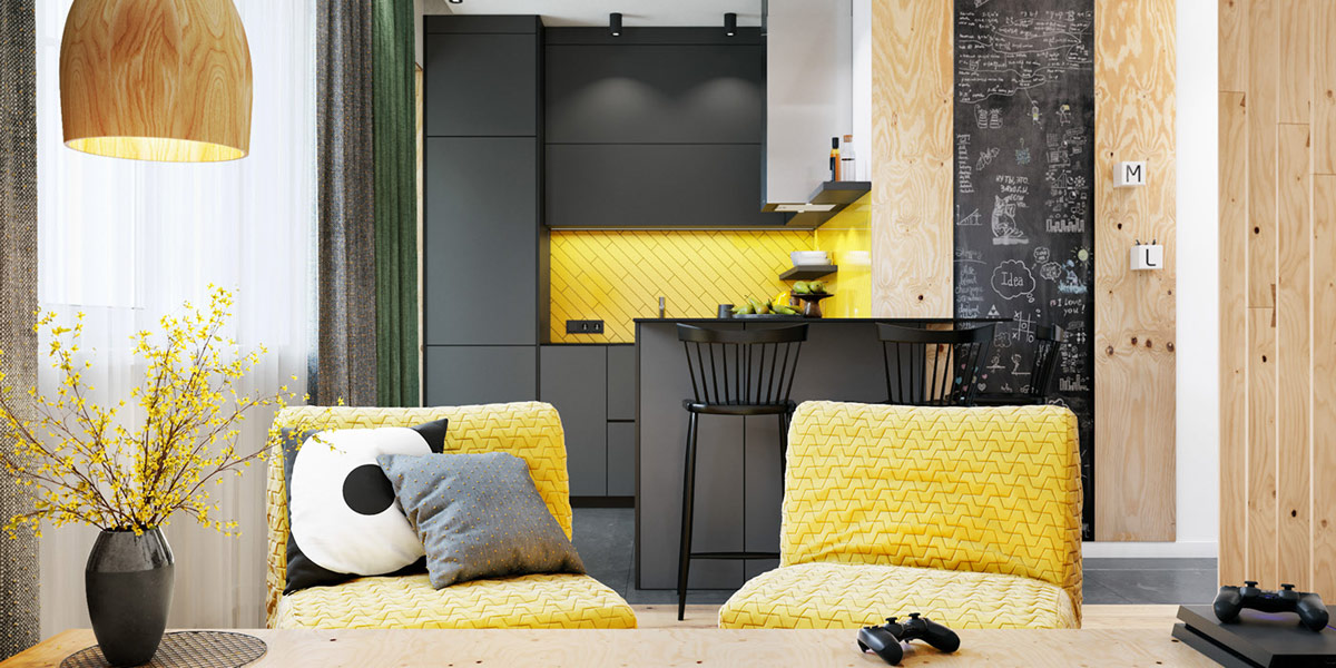 hình ảnh một góc phòng khách với hai ghế ngồi màu vàng chanh, cạnh đó là bếp nấu với tường chắn màu vàng, đèn thả trần, những điểm nhấn bằng gỗ