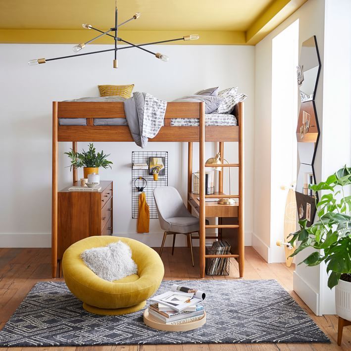 hình ảnh mẫu giường gác xép bằng gỗ tự nhiên, dưới đặt bàn học, tủ ngăn kéo, cạnh đó là ghế thư giãn màu vàng đặt trên thảm trải