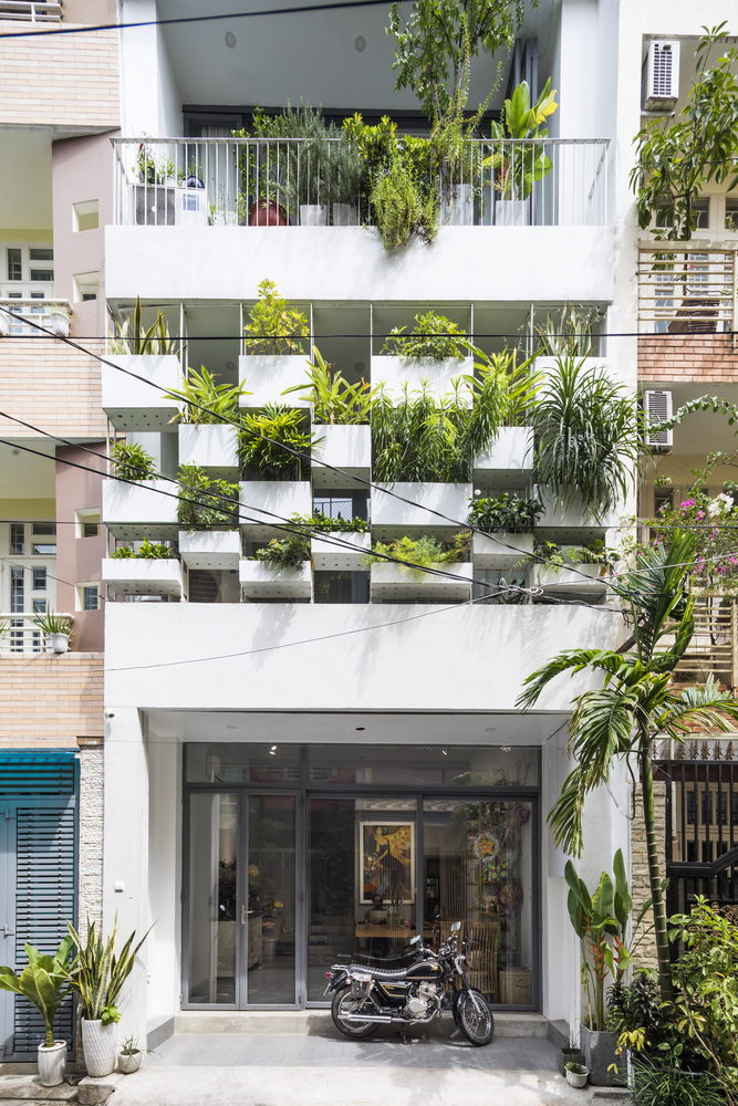 hình ảnh mặt tiền nhà phố 4 tầng với các ô bê tông trồng cây xanh, lan can sắt, cửa kính trong suốt ở tầng trệt