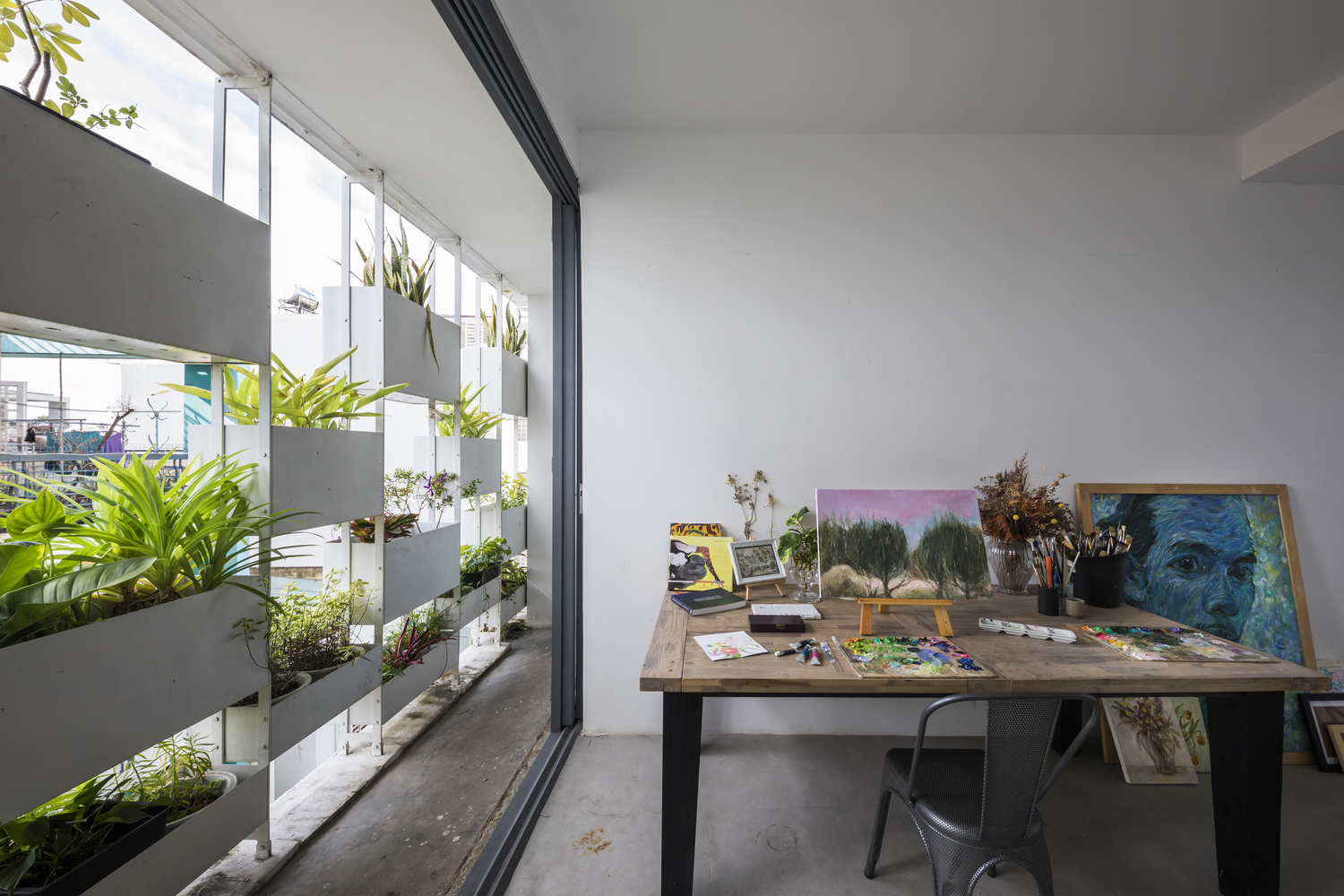 hình ảnh toàn cảnh phòng vẽ trong nhà phố 4 tầng với mặt tiền là các chậu cây trồng giúp hạn chế nắng gắt, tiếng ồn, bụi và tạo sự riêng tư cần thiết