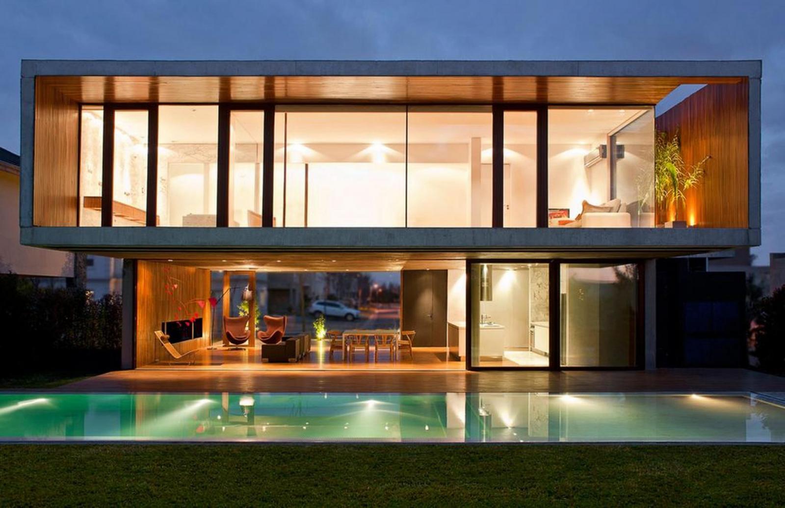 hình ảnh khung cảnh một ngôi nhà về đêm với tường kính cường lực trong suốt, bể bơi xanh mát, ánh đèn vàng