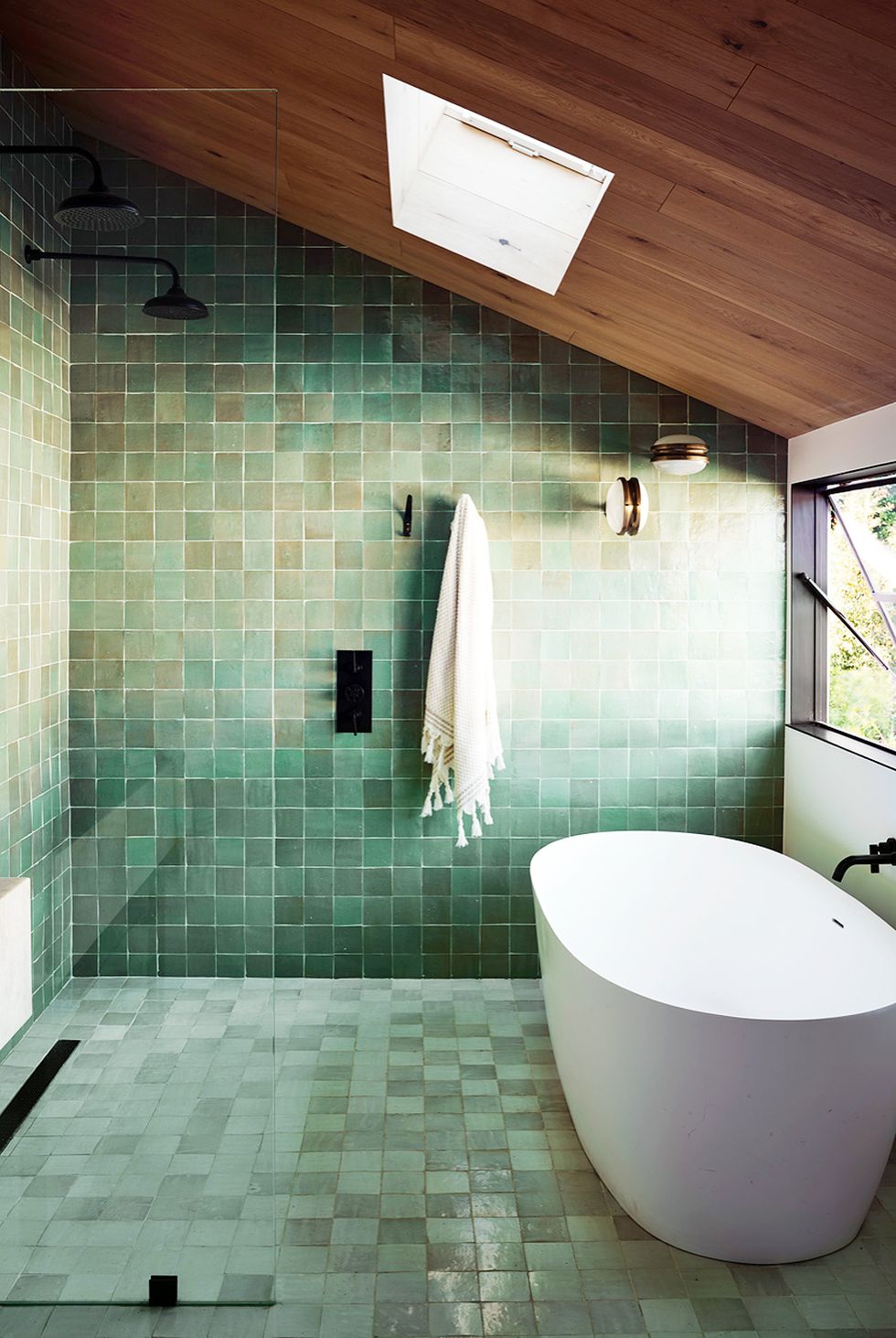 hình ảnh phòng tắm với trần gỗ, tường và sàn ốp gạch màu xanh lá, cửa sổ kính trong suốt, bồn tắm đặt cạnh cửa sổ