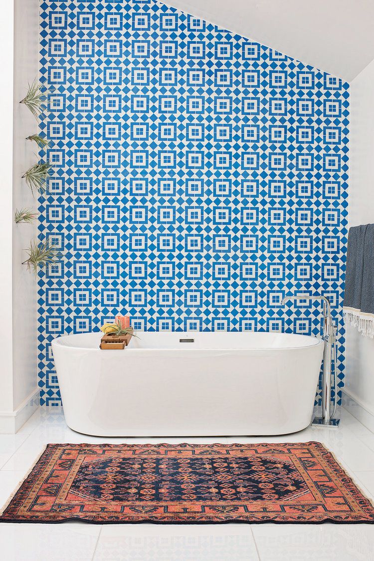 Góc phòng tắm nổi bật với bức tường ốp gạch bông màu xanh, thảm trải dệt thổ cẩm.