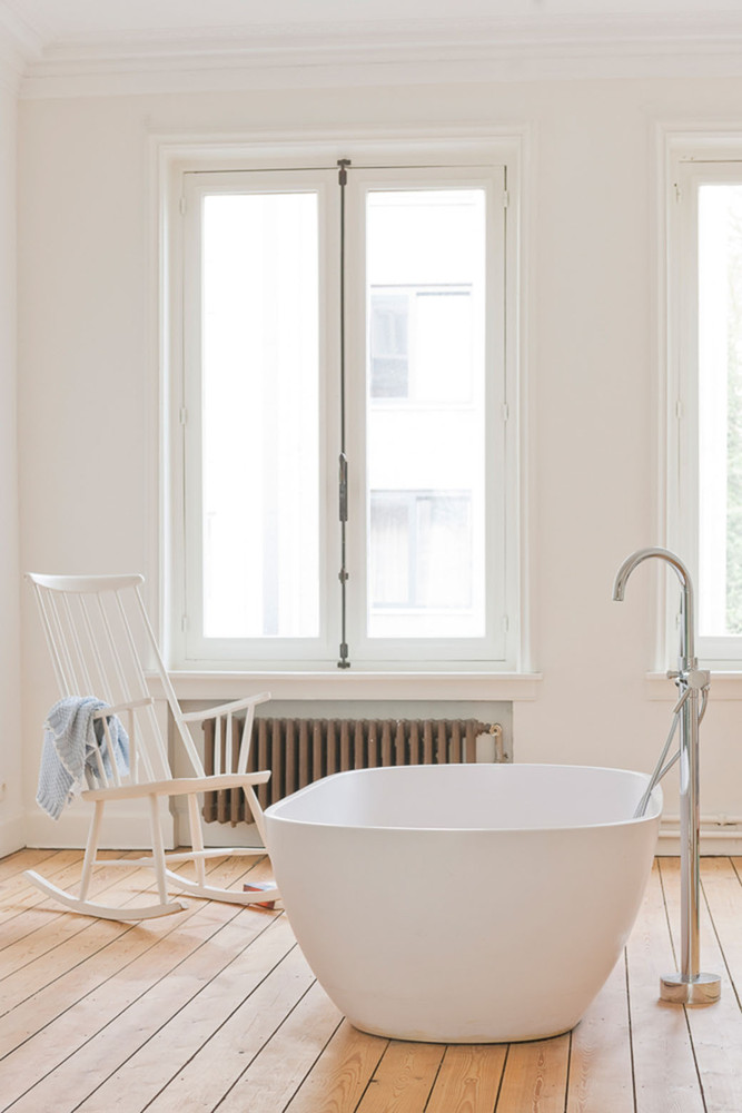hình ảnh phòng tắm ngập tràn ánh sáng với bồn tắm đặt gần cửa sổ kính, ghế ngồi thư giãn
