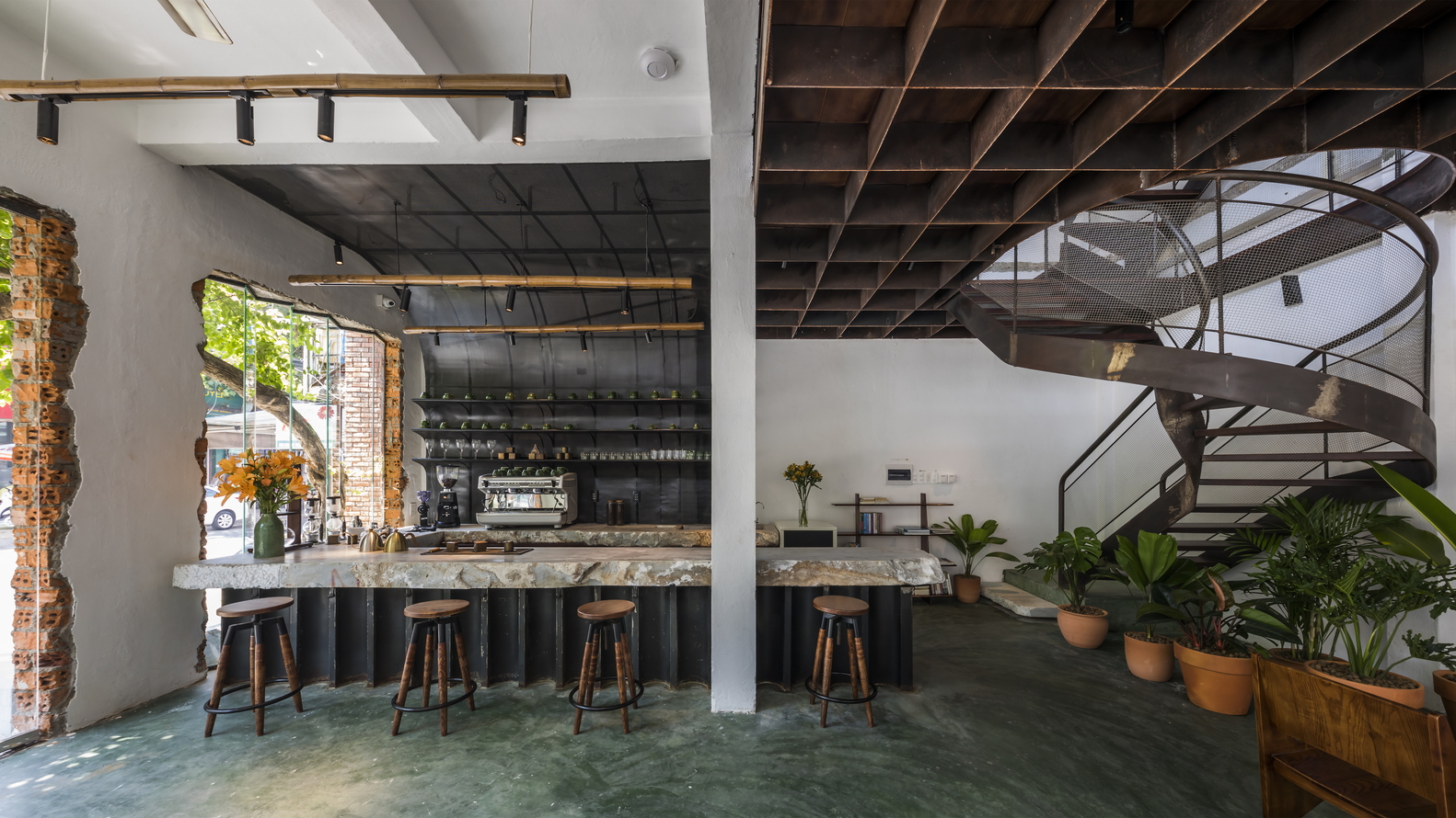 hình ảnh khu vực quầy bar trong quán cà phê với sàn bê tông màu xanh ngọc, ghế bar, kệ gắn tường