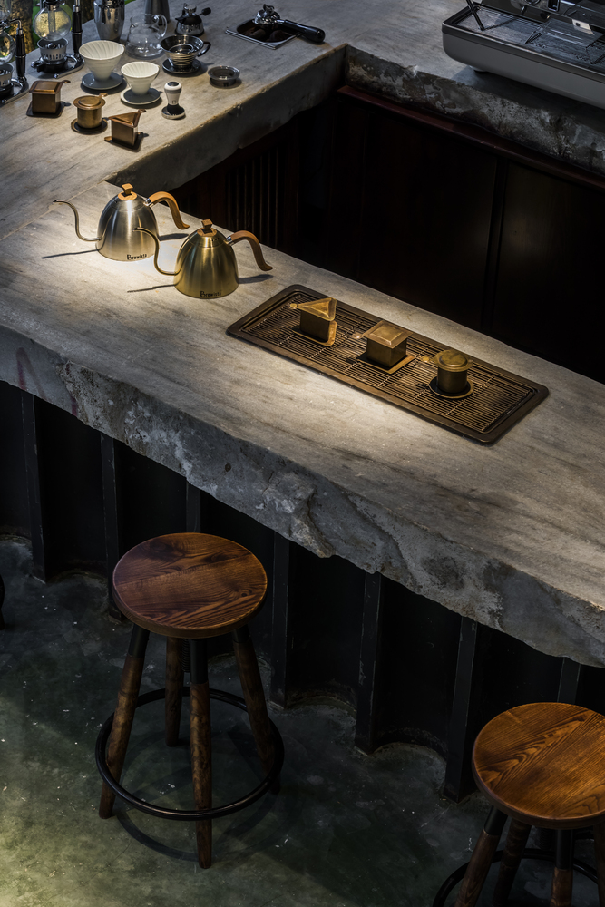 hình ảnh quầy bar quán cà phê với bàn bê tông thô xám, cốc chén bằng đồng sáng bóng
