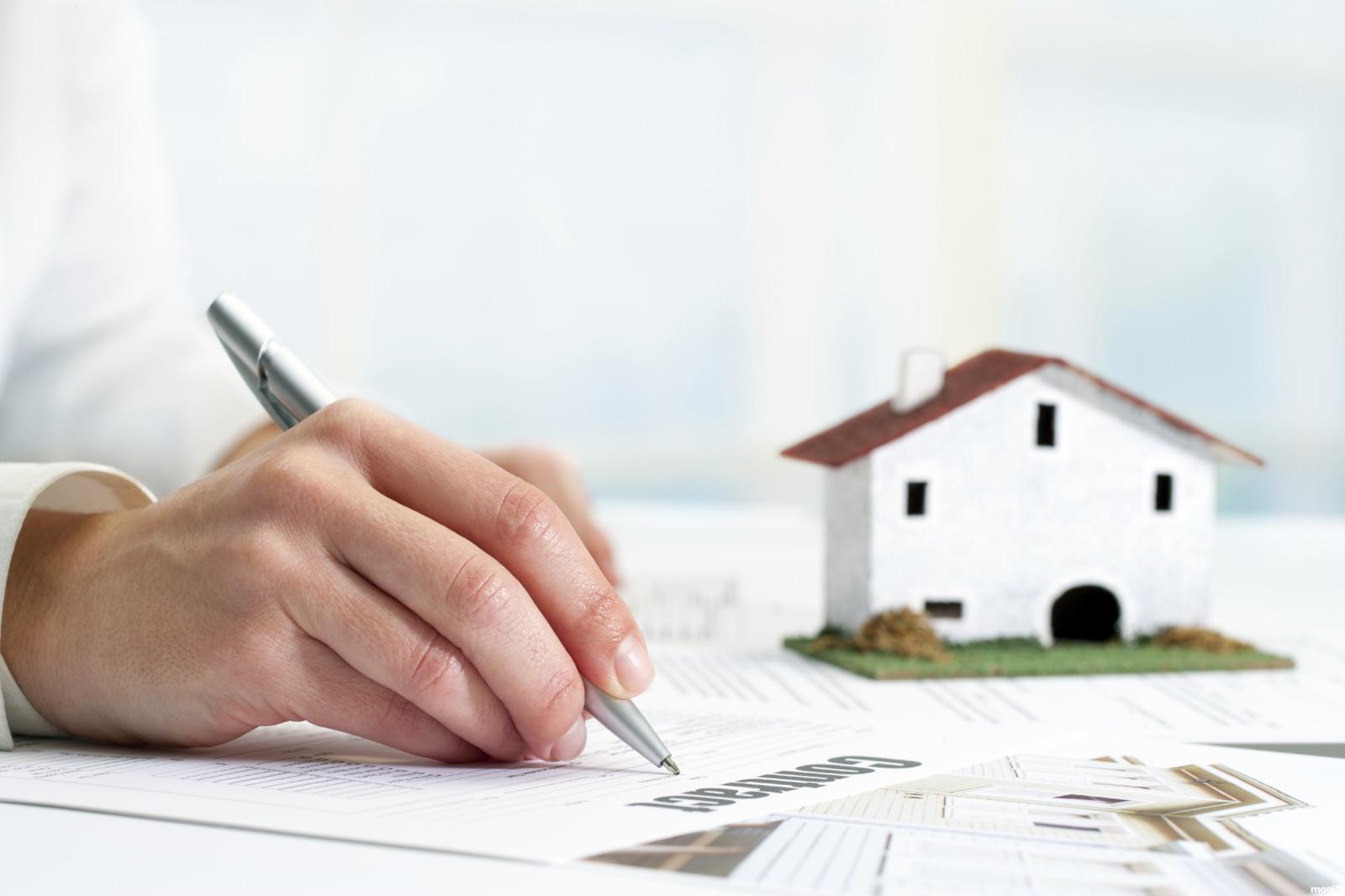 hình ảnh một người đang viết hợp đồng mua bán nhà đất bằng giấy tay
