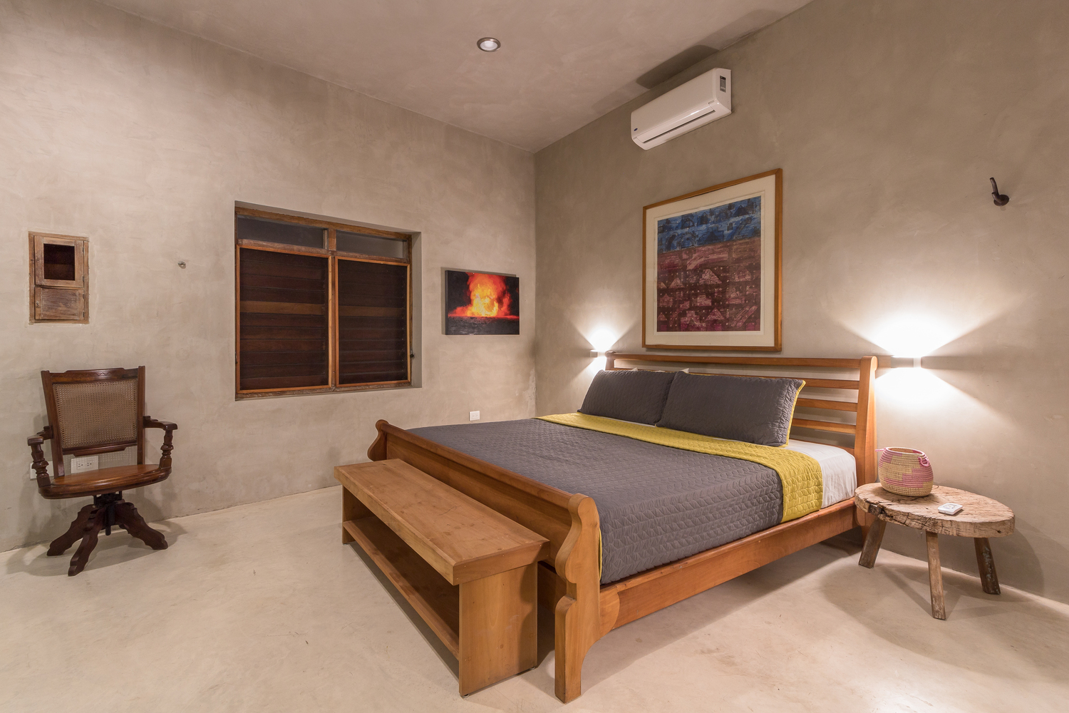 hình ảnh toàn cảnh phòng ngủ phong cách tối giản với giường gỗ, ghế bành thư giãn, bàn đầu giường, tranh trang trí 