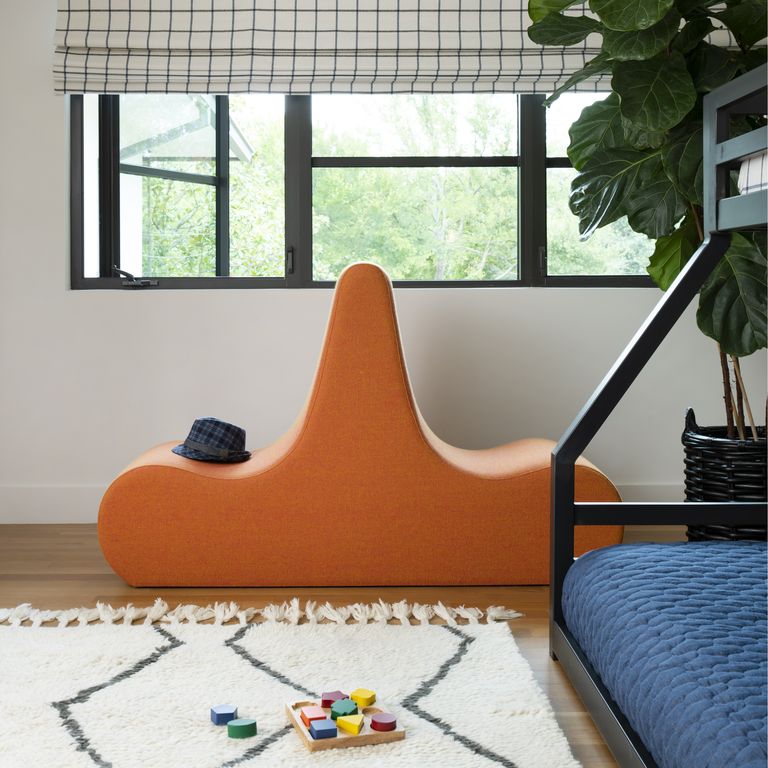 hình ảnh một góc phòng ngủ của trẻ với giường tầng, ga màu xanh dương, thảm trải mềm mại, ghế ngồi độc đáo màu vàng đặt cạnh cửa sổ kính