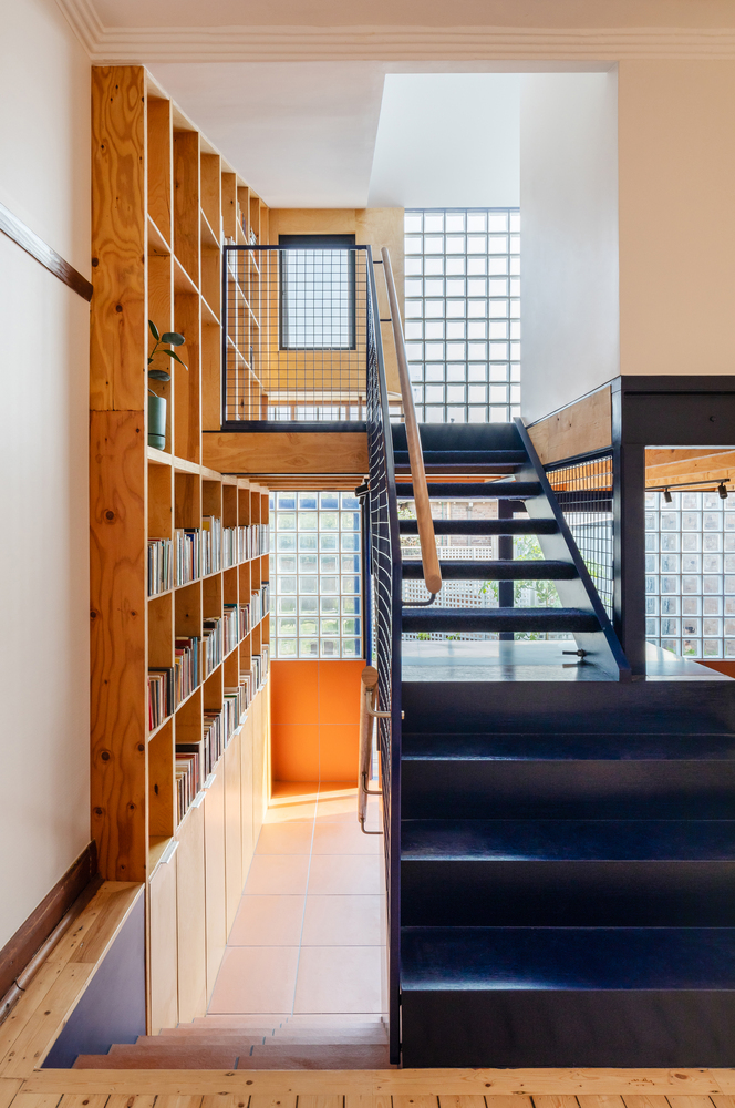 hình ảnh các bậc thang màu xanh nước biển kết nối liền mạch với cầu thang bậc hở dẫn lên phòng đọc ở tầng trên. Lan can lưới vừa thông thoáng, vừa đảm bảo an toàn.