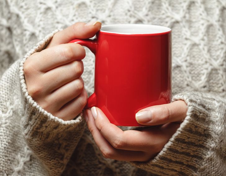 hình ảnh một người đang cầm cốc cà phê màu đỏ tươi