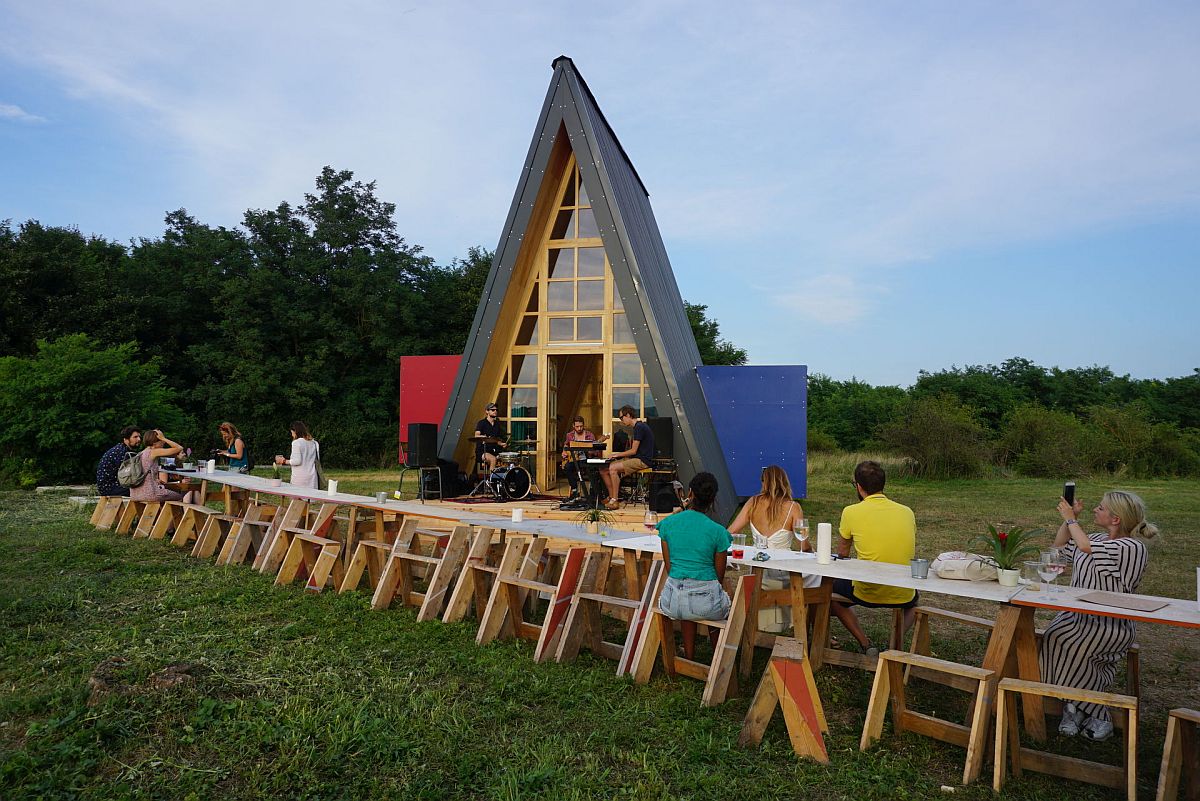hình ảnh toàn cảnh nhà cabin hình chữ A lớn, phía trước có nhiều người ngồi dùng bữa