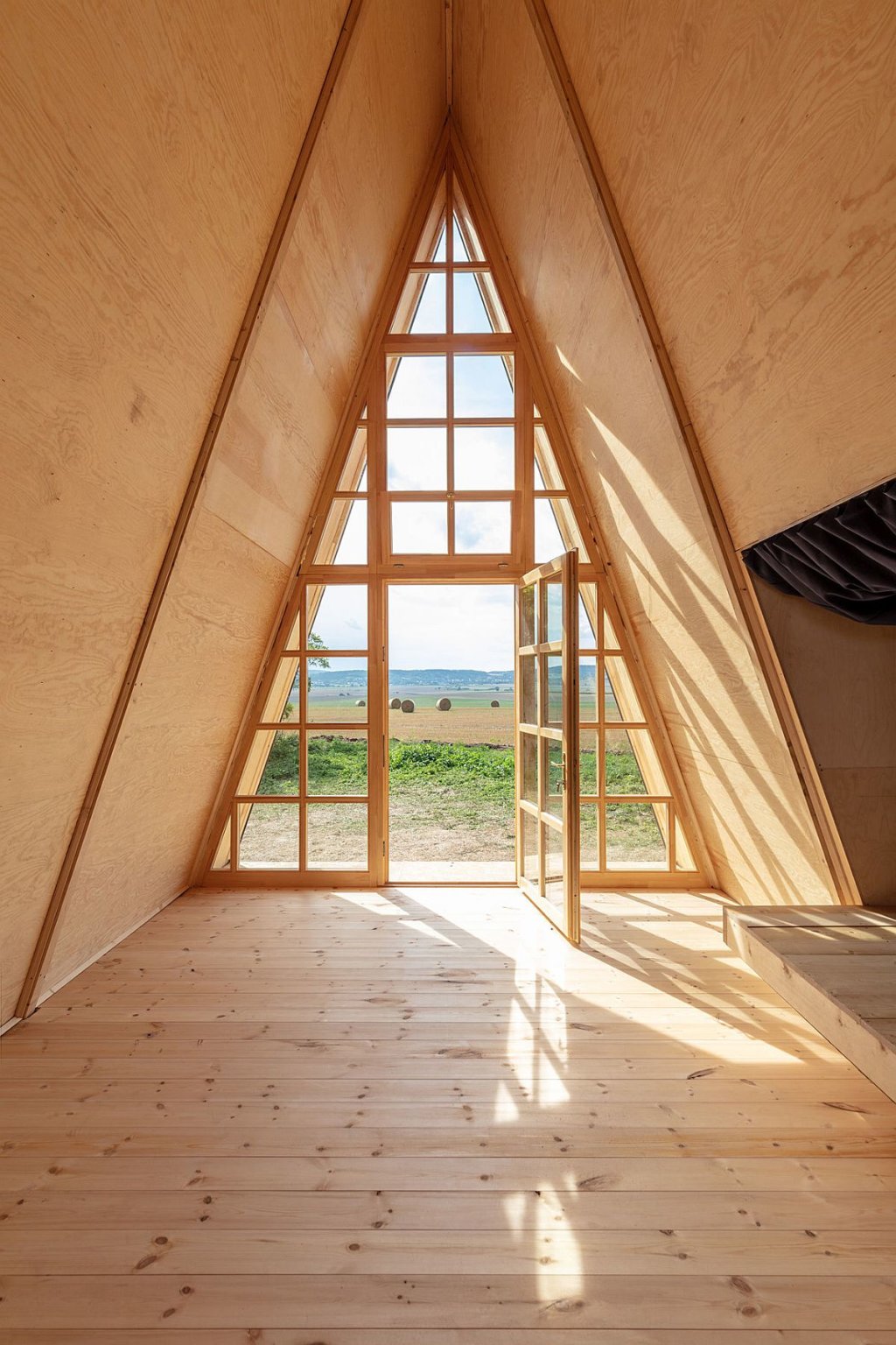 hình ảnh bên trong nhà cabin với trần, tường, sàn ốp lát gỗ thông, cửa kính trong suốt