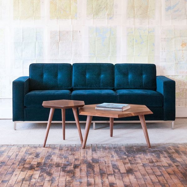 hình ảnh cận cảnh mẫu bàn cà phê gỗ hình học bắt mắt, cạnh đó là sofa màu xanh dương