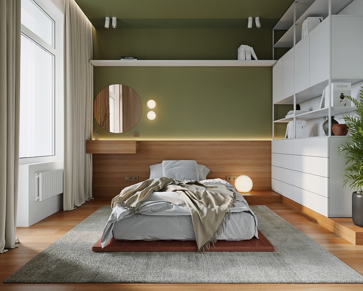 hình ảnh phòng ngủ với giường thấp sàn, tường đầu giường sơn màu xanh lá, gương tròn treo tường, kệ gỗ, đèn LED