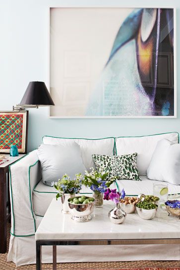 hình ảnh một góc phòng khách với tường sơn trắng, sofa tráng khung viền màu xanh lá