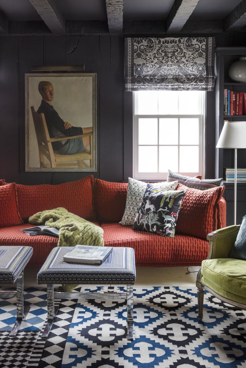 hình ảnh phòng khách nhỏ ấn tượng với tường sơn màu xám đen, sofa màu cam, tranh chân dung treo tường