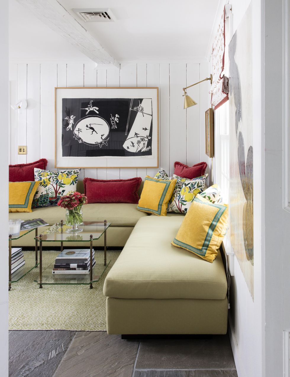 hình ảnh phòng khách nhỏ với tường và trần sơn trắng, sofa xanh als nhạt, gối tựa màu sắc, bàn trà kính, tranh nghệ thuật treo tường