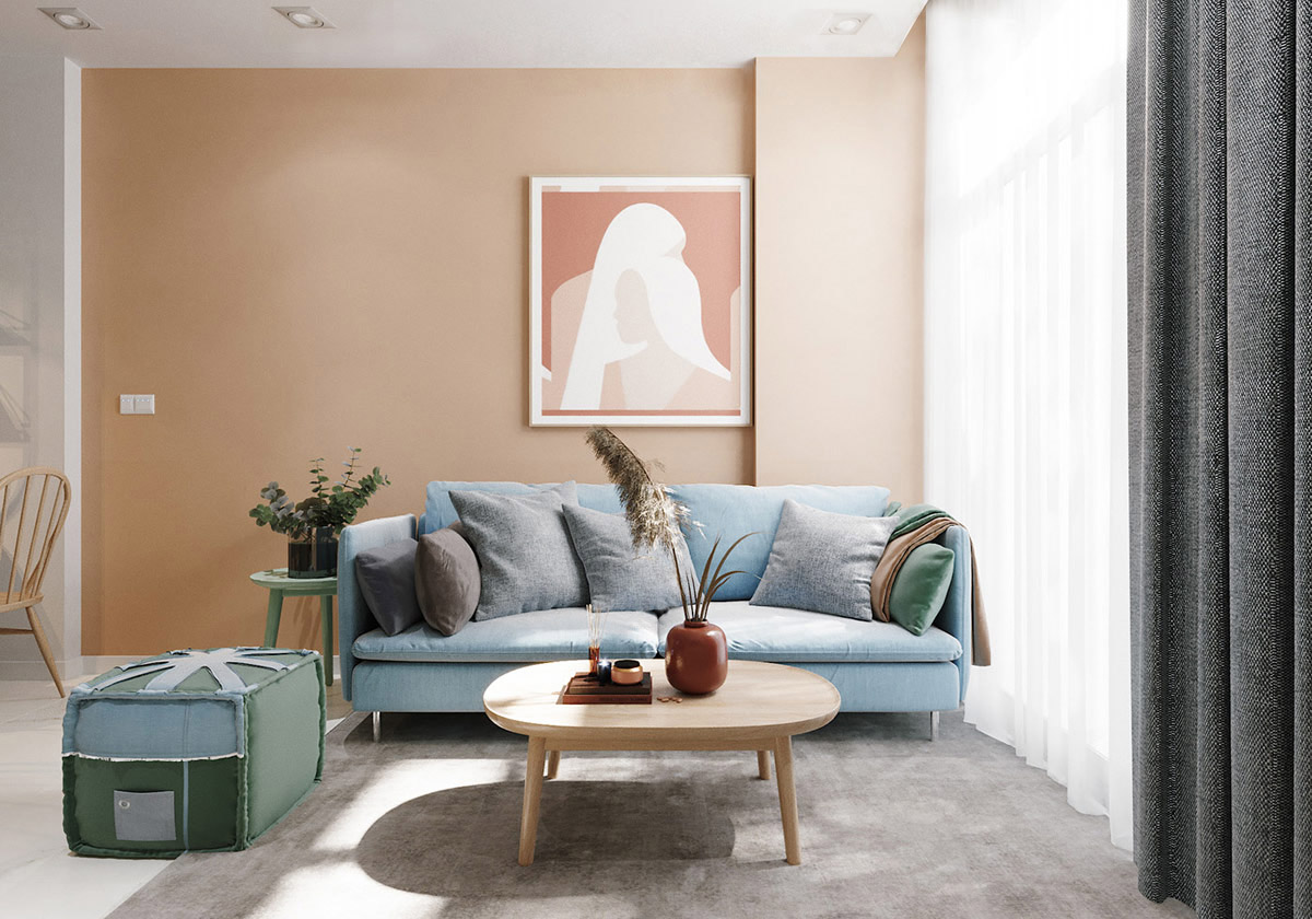 hình ảnh toàn cảnh phòng khách với bàn trà gỗ đặt trên thảm màu xám, ghế sofa xanh dương, ghế phụ xanh lá, tranh tường màu hồng đất ấm áp