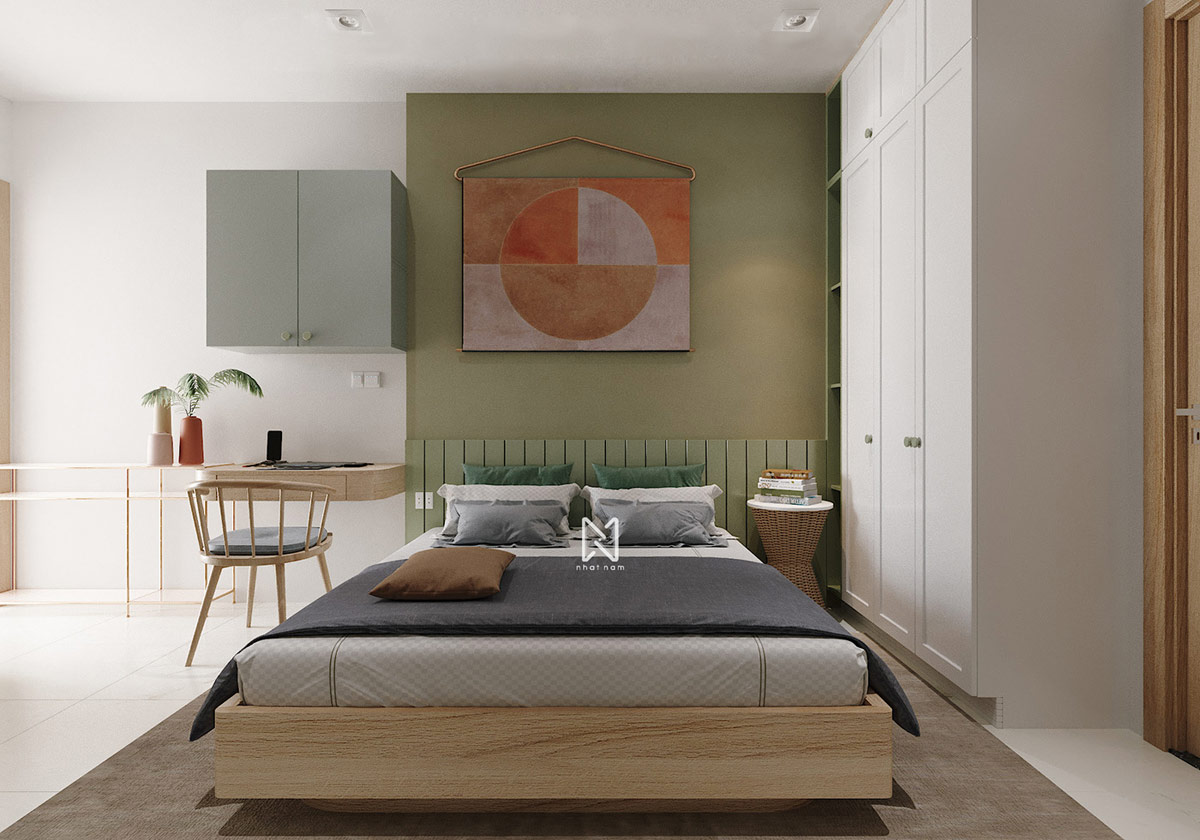 hình ảnh toàn cảnh phòng ngủ trong căn hộ 66m2 với giường đôi, tường đầu giường sơn xanh, tranh tường màu cam đất, bàn làm việc gắn tường, tủ tường, tủ quần áo màu trắng