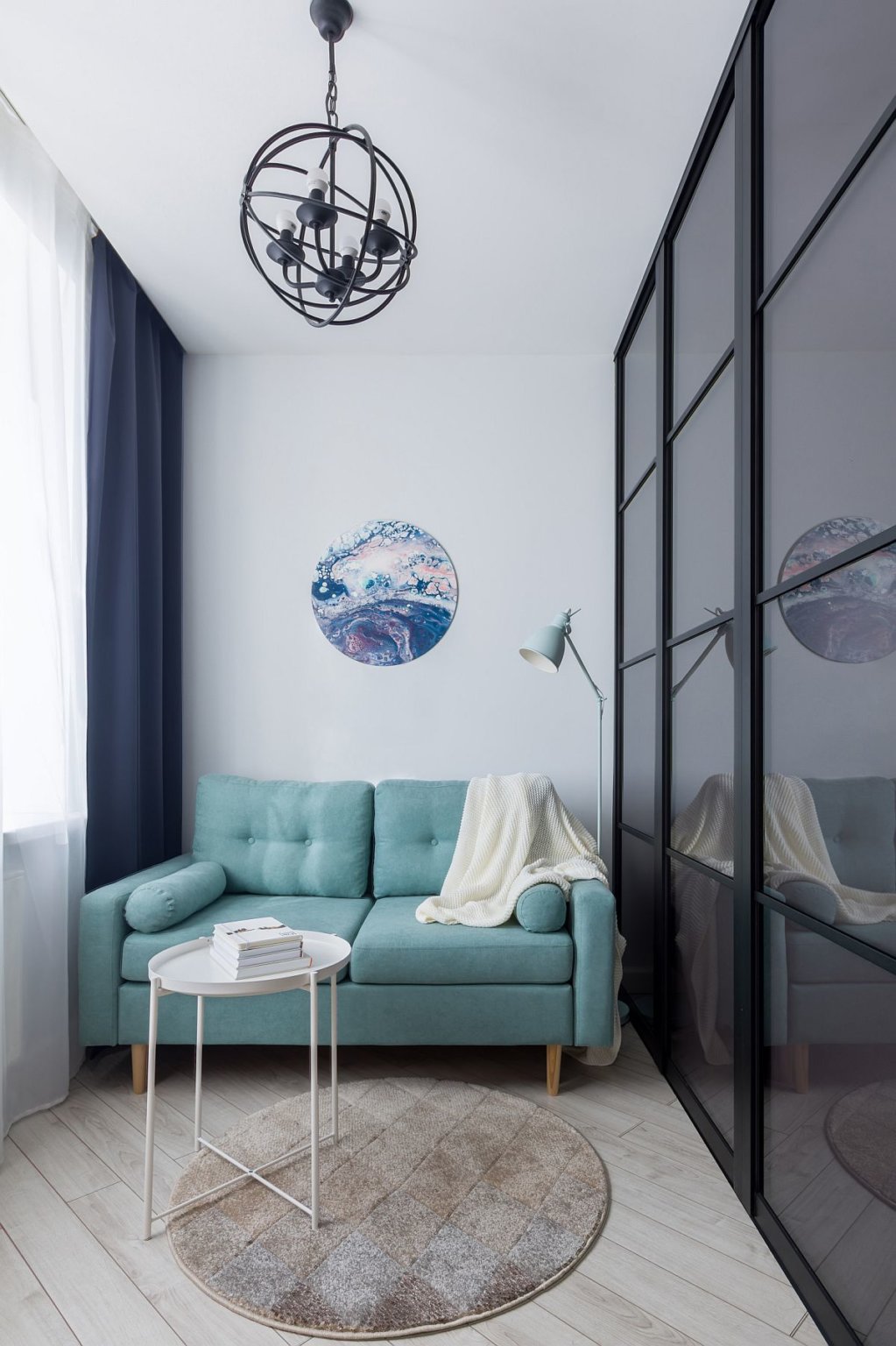 hình ảnh phòng khách căn hộ studio nhỏ với ghế sofa màu xanh da trời, bàn tròn bằng kim loại đặt trên thảm trải
