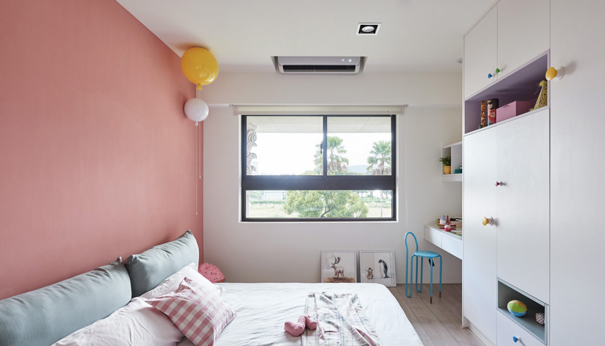 hình ảnh phòng ngủ của trẻ với bức tường sơn màu hồng đất, bàn ghế, tủ màu trắng