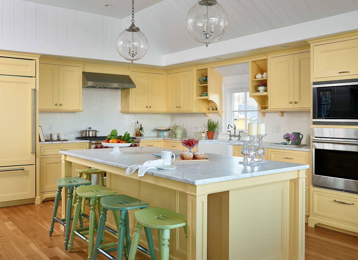 hình ảnh phòng bếp màu vàng mơ chủ đạo với ghế bar màu xanh lá và pastel tạo điểm nhấn