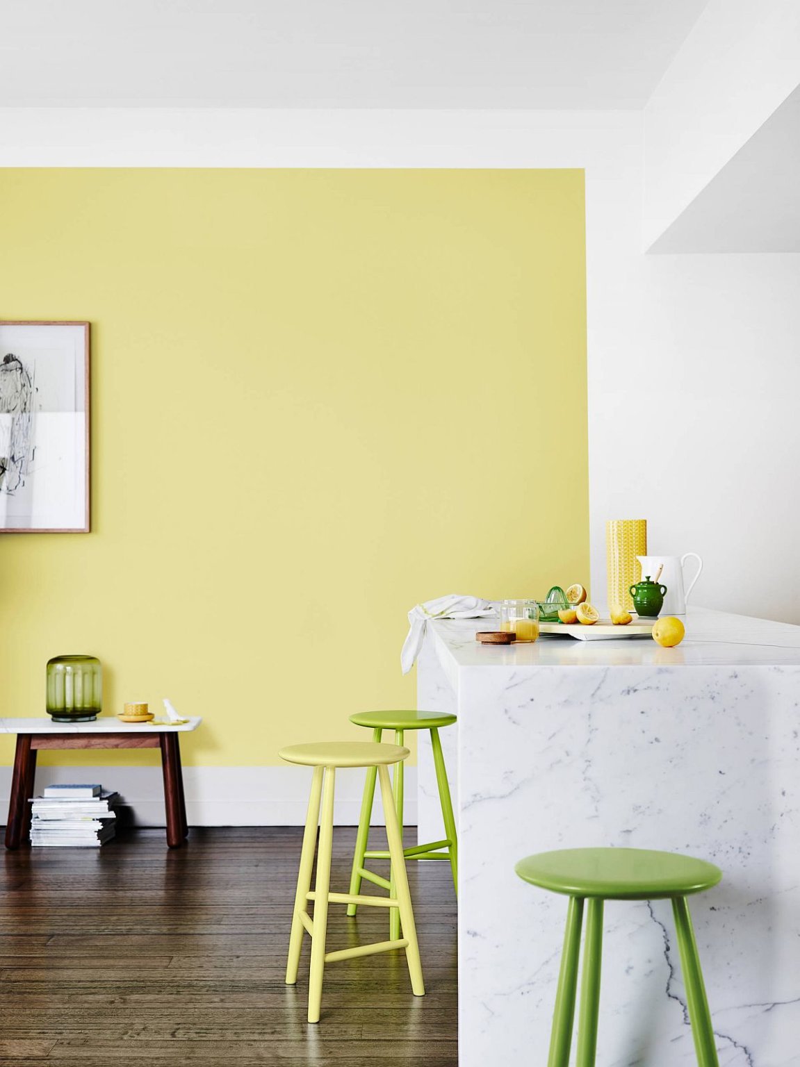 hình ảnh góc phòng bếp hiện đại với tường sơn màu vàng chanh, ghế bar xanh lá, bàn đảo ốp đá cẩm thạch
