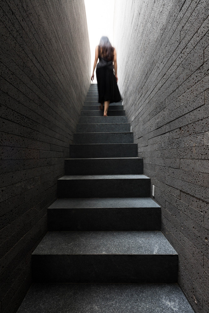 hình ảnh cô gái mặc váy đen bước lên cầu thang màu xám đen
