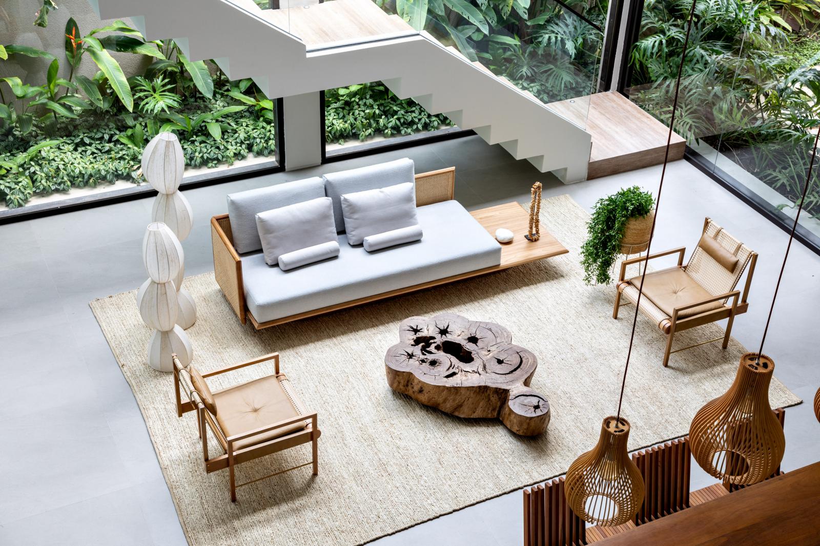 hình ảnh phòng khách ở tầng trệt nhìn từ trên cao với sofa gỗ bọc nệm màu trung tính, bàn trà gỗ nguyên khối