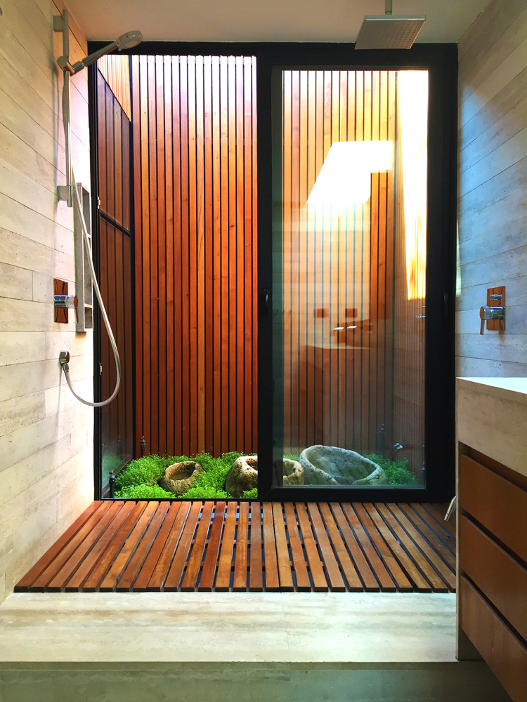hình ảnh phòng tắm phong cách mở ới tường ốp gỗ, cạnh đó là tiểu cảnh giếng trời