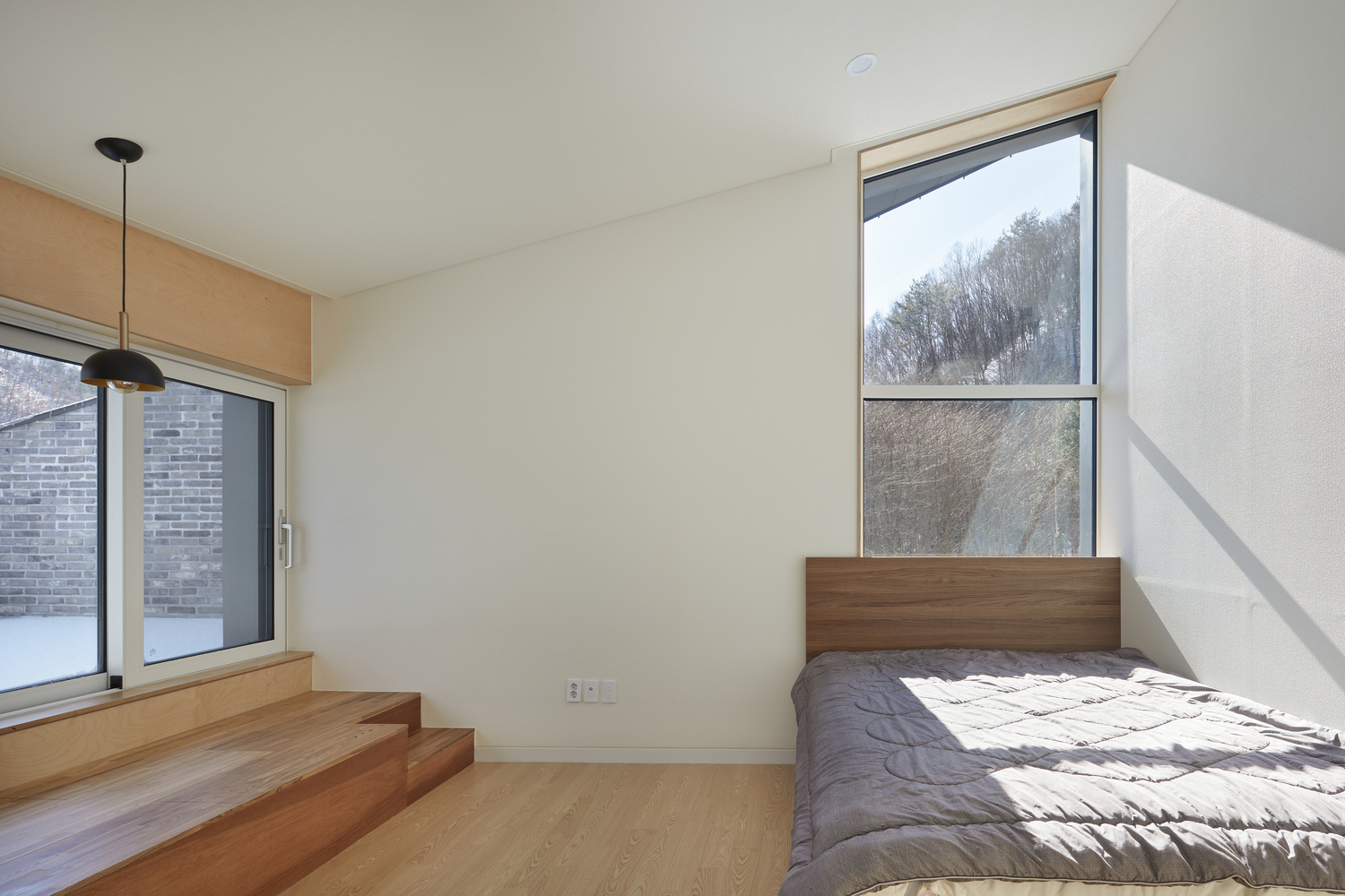 hình ảnh phòng ngủ trong nhà mái dốc với giường gỗ mộc mạc, cửa sổ kính trong suốt