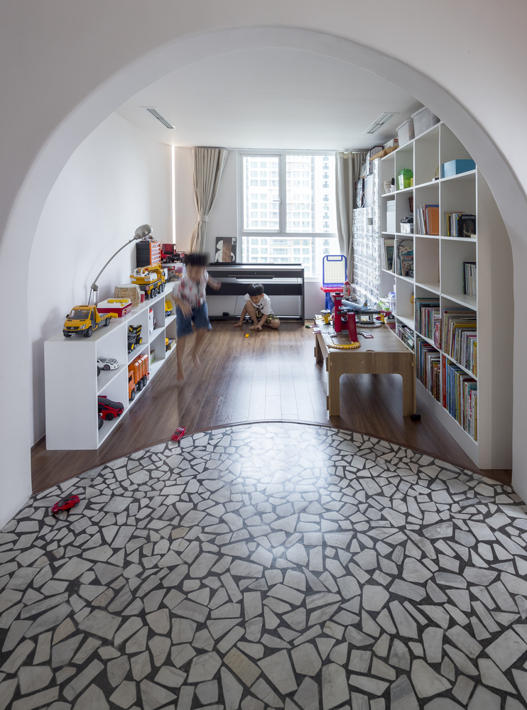 hình ảnh phòng chơi cho bé trong căn hộ duplex với sàn lát gỗ, gạch terrazzo, giá kệ để đồ chơi, khung cửa hình vòm