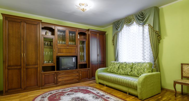 hình ảnh phòng khách với sofa xanh lá cây, tủ gỗ lưu trữ tích hợp kệ đặt tivi
