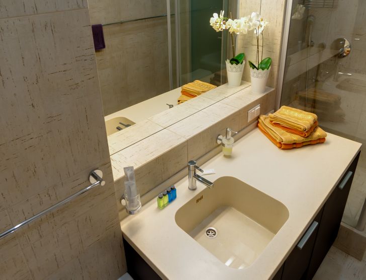 hình ảnh phòng tắm đơn giản, nổi bật với chiếc khăn tắm màu vàng đặt trên bệ rửa