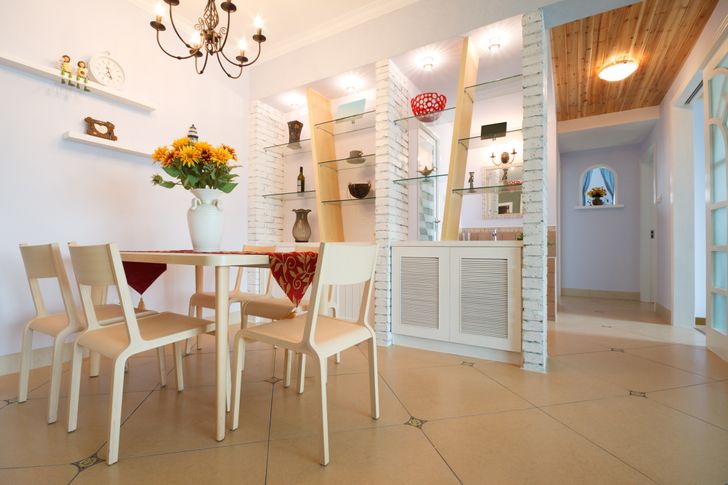 hình ảnh một phòng ăn hiện đại tông màu trắng sáng chủ đạo, đèn chùm trang trí, bình hoa hướng dương đặt trên bàn