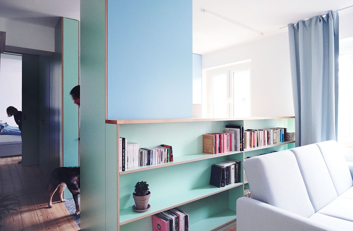 Phòng khách của căn hộ ngăn cách với nhà bếp bằng tường lửng kết hợp giá sách gọn đẹp.