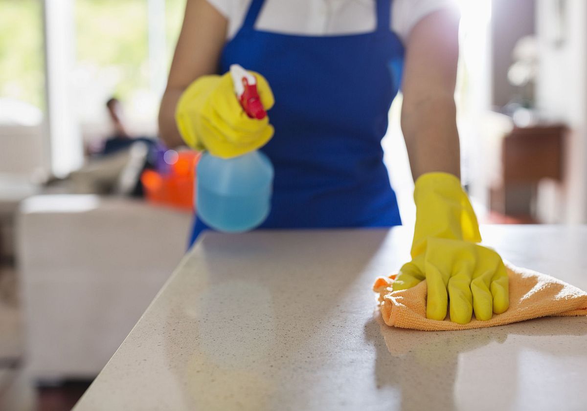 hình ảnh một người phụ nữ đang dùng bình xịt vệ sinh bàn bếp