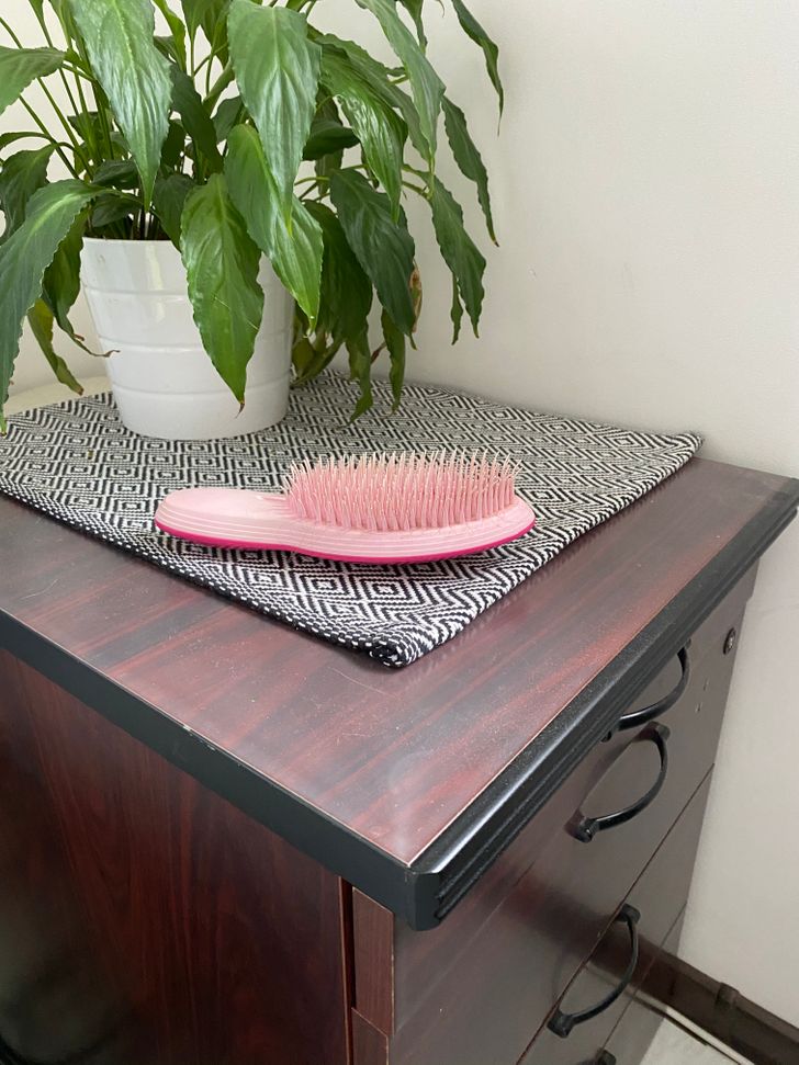 lược chải tóc màu hồng đặt trên bàn gỗ sẫm màu