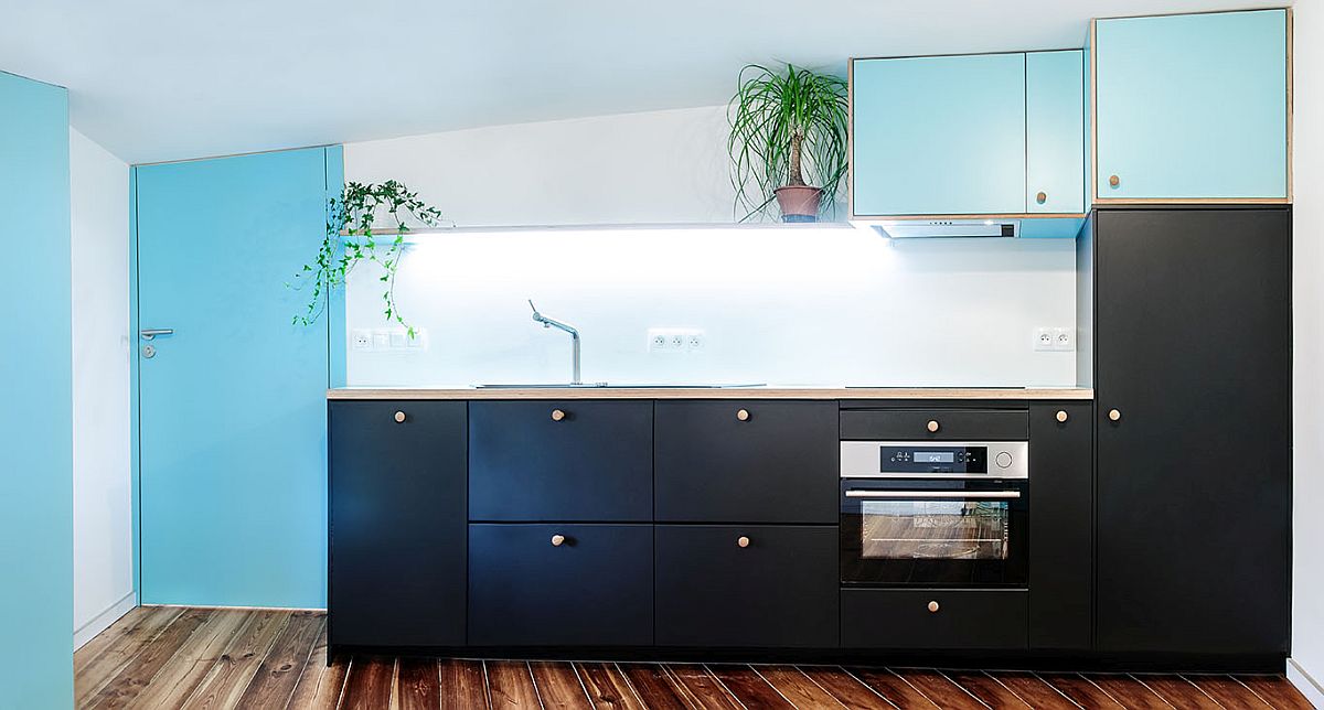 Nếu như tông màu trắng và xanh lam tạo cảm giác thoáng rộng cho căn hộ áp mái thì hệ tủ bếp màu đen giúp không gian có chiều sâu hơn.