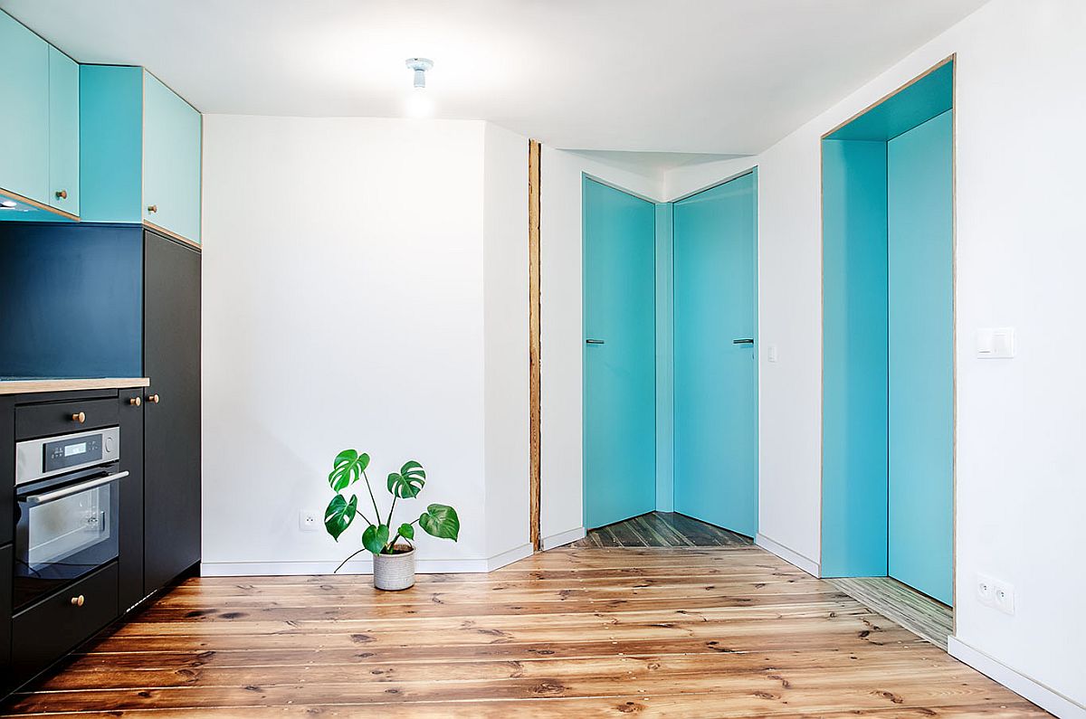 Chất liệu gỗ, cửa ra vào và cửa một vài tủ bếp màu xanh dương tạo điểm nhấn tươi mát cho căn hộ áp mái màu trắng chủ đạo.