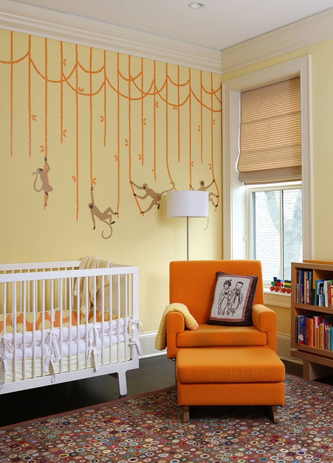 phòng cho trẻ sơ sinh với giường cũi màu trắng, ghế tựa màu cam và tường sơn vàng nhạt
