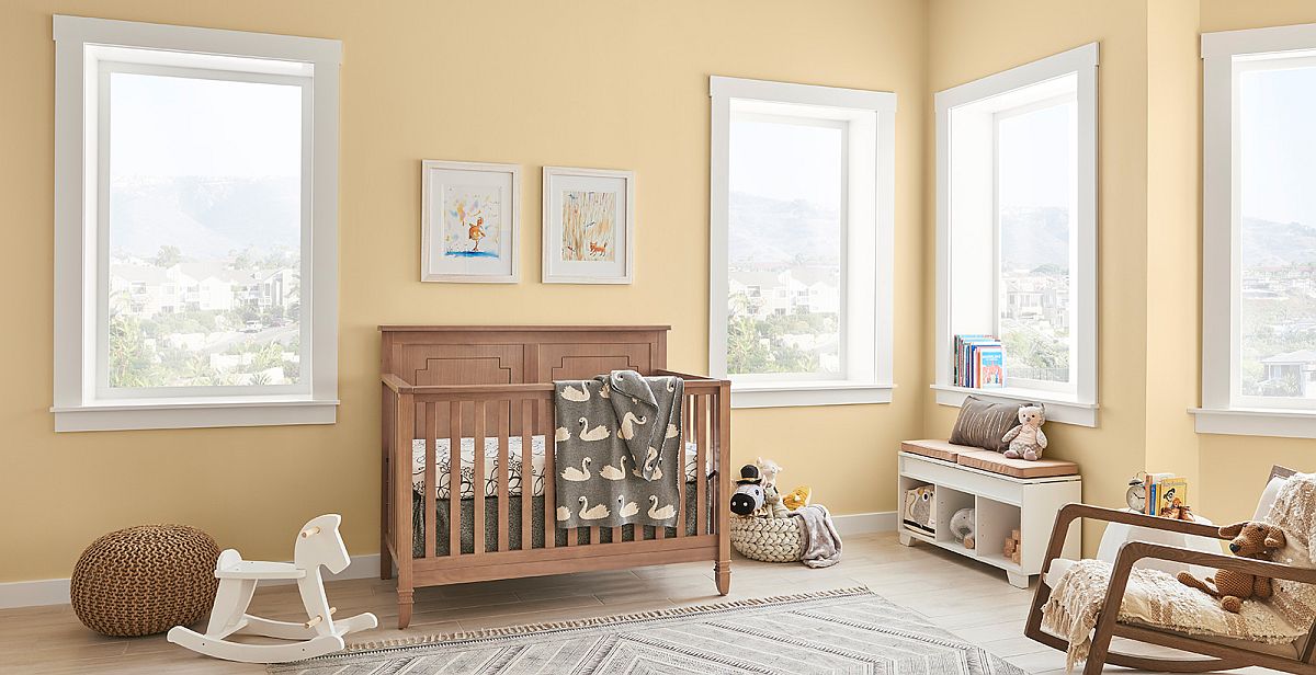 phòng ngủ của trẻ với tường sơn màu vàng nhạt, tủ kệ bằng gỗ màu nâu ấm áp