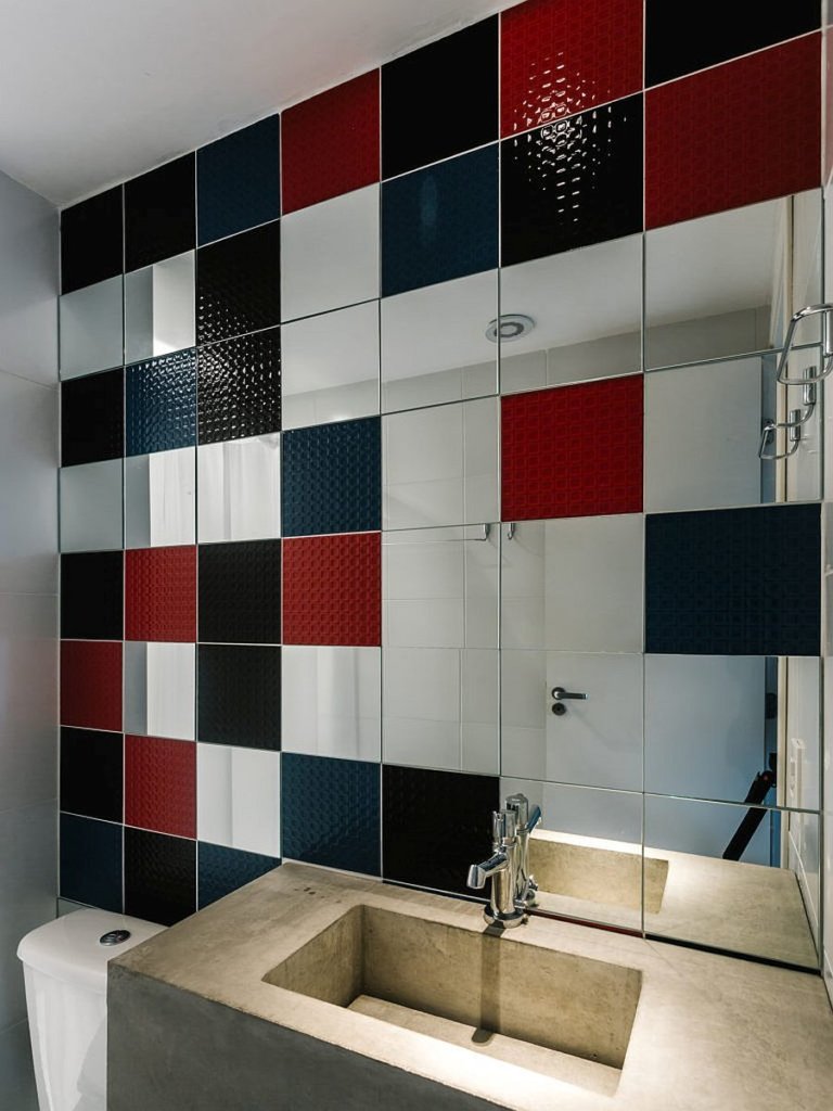Phòng tắm căn hộ 65m2 cực ấn tượng với tường lát gạch nhiều màu sắc đen, đỏ và xanh tương phản với bề mặt xi măng xám ở bồn rửa.