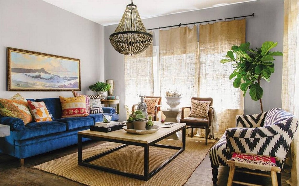 phòng khách với sofa xanh coban, bàn trà vuông, thảm cói, rèm vải mộc