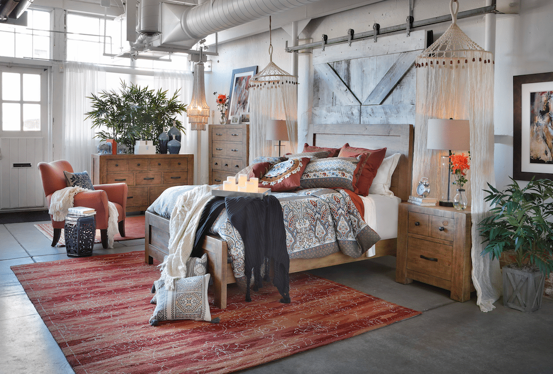 Phòng ngủ với giường nệm êm ái, thảm trài và thế tựa màu cam đất, tủ gỗ lưu trữ