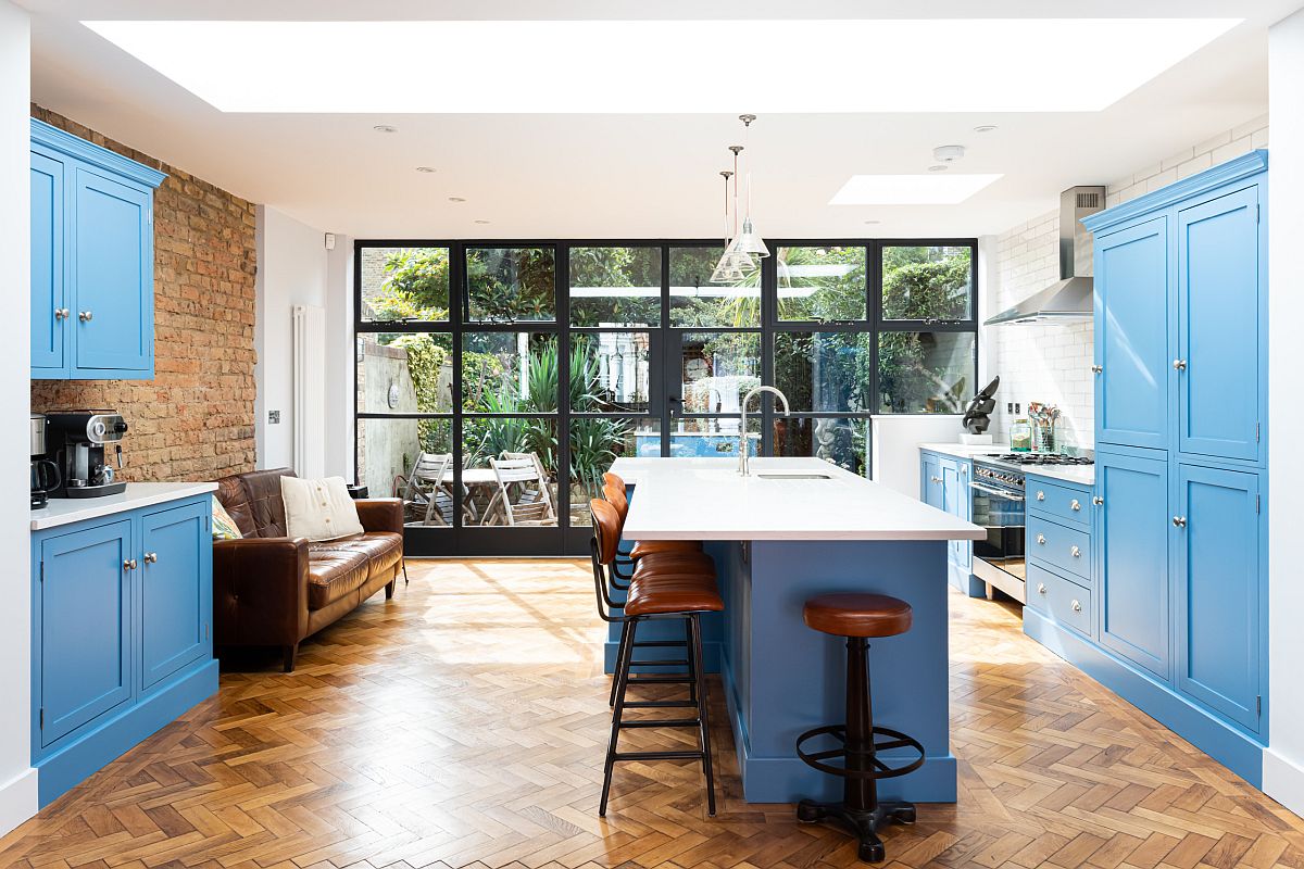 Nhà bếp hiện đại với tủ màu xanh lam, bàn đảo thông minh và bức tường gạch lộ ấn tượng.